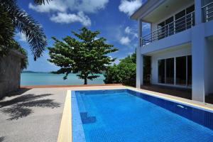 a swimming pool in front of a house at Chalong Beach Front Residence in Rawai Beach