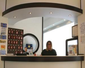 una mujer sentada en un mostrador frente a un espejo en Hotel Roby, en Lido di Jesolo
