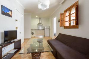 ein Wohnzimmer mit einem Sofa und einem Tisch sowie eine Küche in der Unterkunft Apartamento en pleno centro, WIFI, ideal in Granada