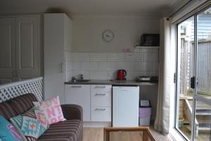 a small kitchen with a refrigerator and a couch at The Lighthouse in Auckland