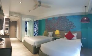 ein Schlafzimmer mit 2 Betten und eine Wand mit einem Fischgemälde in der Unterkunft Lagùn Hotel in El Nido