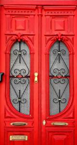 una porta rossa con due finestre sopra di Hostel A Casa da Árvore a Faro