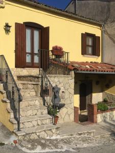 een geel huis met een trap en een raam bij I Malatesta in Boiano