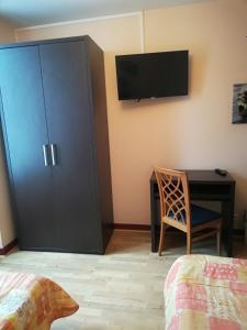 a bedroom with a desk and a cabinet with a television at Hôtel de la Poste in Limoges