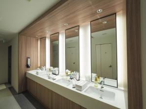 La salle de bains est pourvue de 3 lavabos et d'une rangée de miroirs. dans l'établissement Leo Yu Capsule Hotel Funabashi, à Funabashi