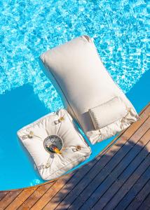 a chaise lounge on a wooden deck next to a swimming pool at Belvedere Andros in Batsi