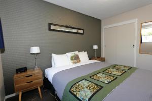 a bedroom with a large bed and a nightstand with a bed sidx sidx sidx at Aden Motel in Te Anau