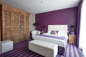ein Schlafzimmer mit einem großen Bett und einer lila Wand in der Unterkunft Hotel Kastel & Spa avec piscine d'eau de mer chauffée in Bénodet