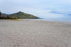 a sandy beach with a mountain in the background at Beach House Zambales in San Antonio