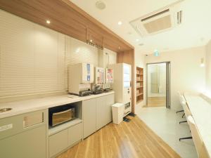 a large kitchen with white cabinets and a sink at Leo Yu Capsule Hotel Funabashi in Funabashi