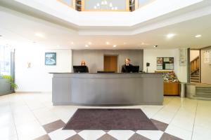 Eine Frau, die an einem Tresen in einer Lobby sitzt. in der Unterkunft Hotel Golden Park Budapest in Budapest