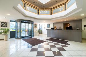 a woman standing at a reception desk in a lobby at Hotel Golden Park Budapest in Budapest