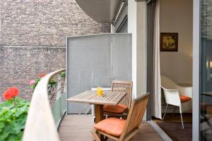 einen Holztisch und Stühle auf dem Balkon in der Unterkunft Residhotel Imperial Rennequin in Paris