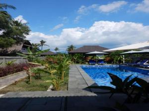 a pool at a resort with chairs and trees at Turtle Garden Hotel in Gili Islands