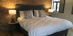 a bedroom with a bed with pillows and two lamps at Hayburg House in Robertson +28 photos