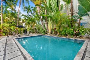 a swimming pool with palm trees in front of a house at Hudson Apartments in Miami Beach