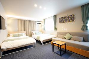 a hotel room with two beds and a couch at Koti Sopo Universal Bay 1 by Liaison in Osaka