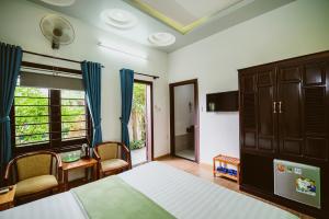 1 dormitorio con 1 cama, mesa y sillas en Tue Tam Garden Villa en Hoi An