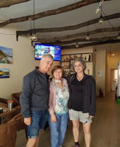 3 Personen, die sich für ein Bild in einem Wohnzimmer ausgaben in der Unterkunft Dimitri Guest House in Përmet