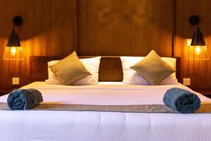 a bedroom with a large bed with blue slippers on it at Subaseth Villa in Anuradhapura