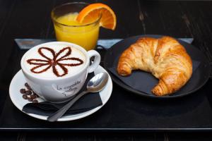 una tazza di caffè e un cornetto e un bicchiere di succo d'arancia di Dante Relais a Napoli