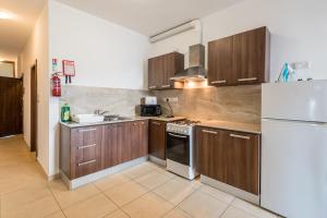 una cucina con armadi in legno e frigorifero bianco di Seashells 2 Bedroom Apartments with terrace, just off the Bugibba promenade - by Getwaysmalta a San Pawl il-Baħar