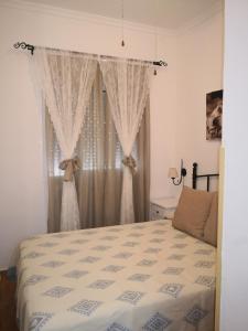 a bedroom with a bed and a window with curtains at Tabano in Chipiona +22 photos