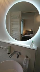 ein Badezimmer mit einem weißen Waschbecken und einem Spiegel in der Unterkunft Hotel in Herrenhausen in Hannover + 37 Fotos