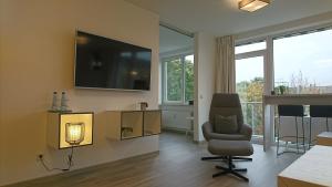 ein Wohnzimmer mit einem Stuhl und einem TV an der Wand in der Unterkunft Hotel in Herrenhausen in Hannover