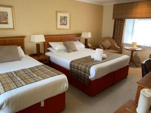 una habitación de hotel con 2 camas y una silla en The Winnock Hotel en Drymen