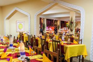 AHG Waridi Beach Resort & SPA في بواني ماكهانجاني: غرفة طعام مع طاولات وكراسي صفراء