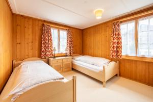 two beds in a room with wooden walls and windows at Chalet Cauma in Flims