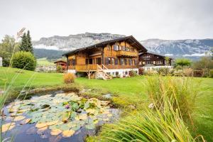 a large wooden house with a pond in front of it at Chalet Cauma in Flims