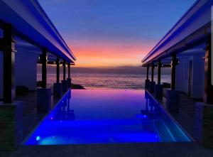 a swimming pool in front of the ocean at sunset at Alegria Water Front Beach House in Alegria