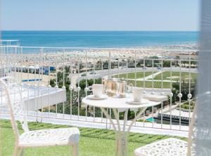 a table and chairs on a balcony with a view of the beach at Hotel Milton Rimini in Rimini