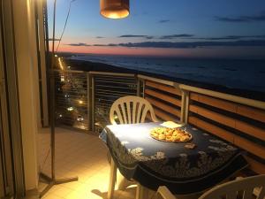 a table with a plate of food on a balcony with the ocean at Appartamento mozzafiato fronte mare in Roseto degli Abruzzi