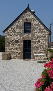 ein Steingebäude mit einem Tisch und Stühlen davor in der Unterkunft La Boulangerie, charmant cocon pour déconnecter in Montfarville