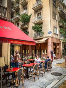 un groupe de personnes assises à des tables à l'extérieur d'un restaurant dans l'établissement API Projects Athens - Cartier Apartment, à Athènes