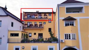 a tall yellow building with people on a balcony at Marktplatz Traunsee LAKE View in Gmunden