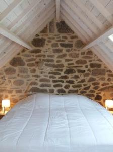 Bett in einem Zimmer mit einer Steinmauer in der Unterkunft La Boulangerie, charmant cocon pour déconnecter in Montfarville