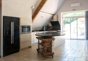 a kitchen with a black refrigerator and a table at Domaine de Janis & Spa in Le Vigan