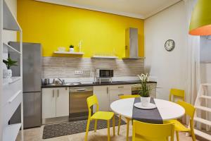 kuchnia z żółtymi ścianami, stołem i krzesłami w obiekcie LEEWAYS APARTMENT in ORIENTE w Madrycie