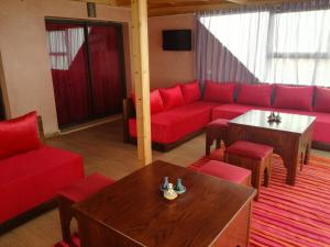 a living room with a red couch and a table at Genova surf house in Imsouane
