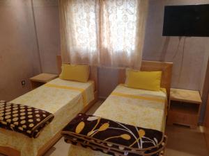 a room with two beds and a tv and a window at Genova surf house in Imsouane