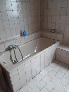 a bath tub in a white tiled bathroom at Ferienwohnung Steffi in Andernach