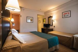 a hotel room with two beds and a lamp at Hotel Corregidor in Segovia