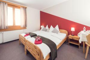 Un dormitorio con una cama grande con zapatos rojos. en Berghaus Diavolezza en Berninahäuser