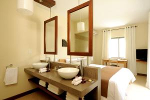 un bagno con due lavandini, un letto e uno specchio di Athena Villas by Fine & Country a Grand Baie