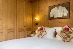 
a bed with white sheets and pillows in a room at Hotel Baita Dei Pini in Bormio

