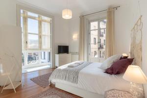 a white bedroom with a bed and two windows at Confort y Diseño con Vistas al Casco Viejo in Bilbao